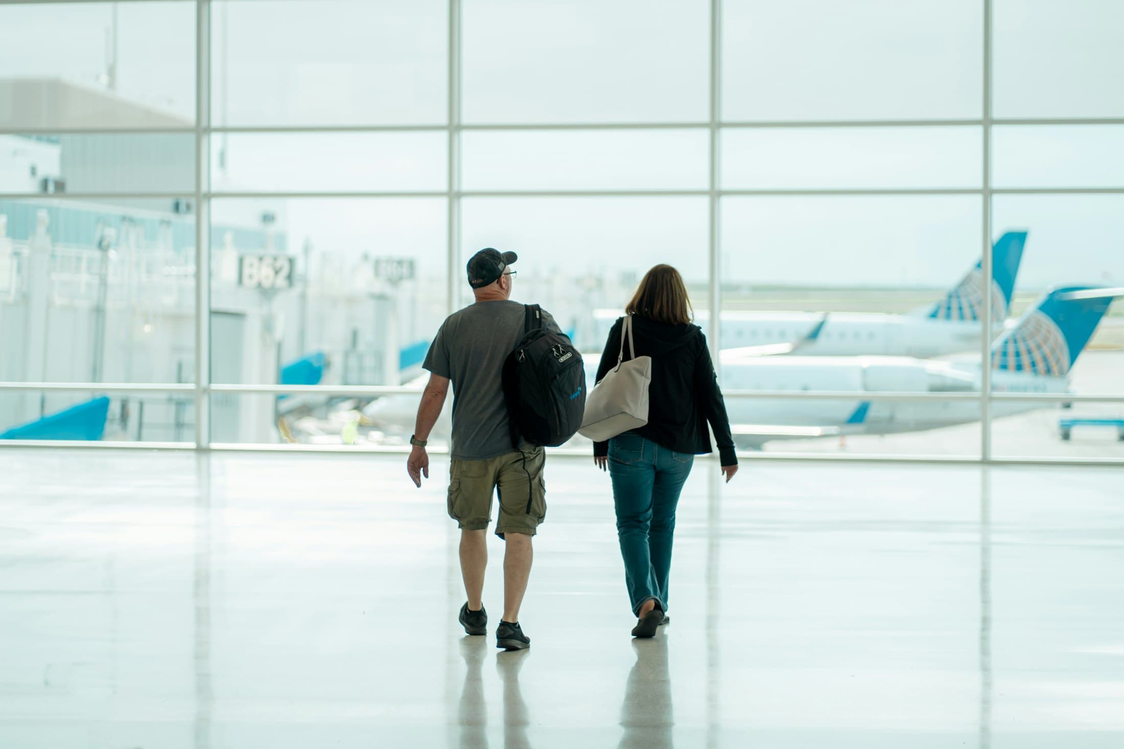 Deux voyageurs traversent un terminal lumineux, valise à la main
