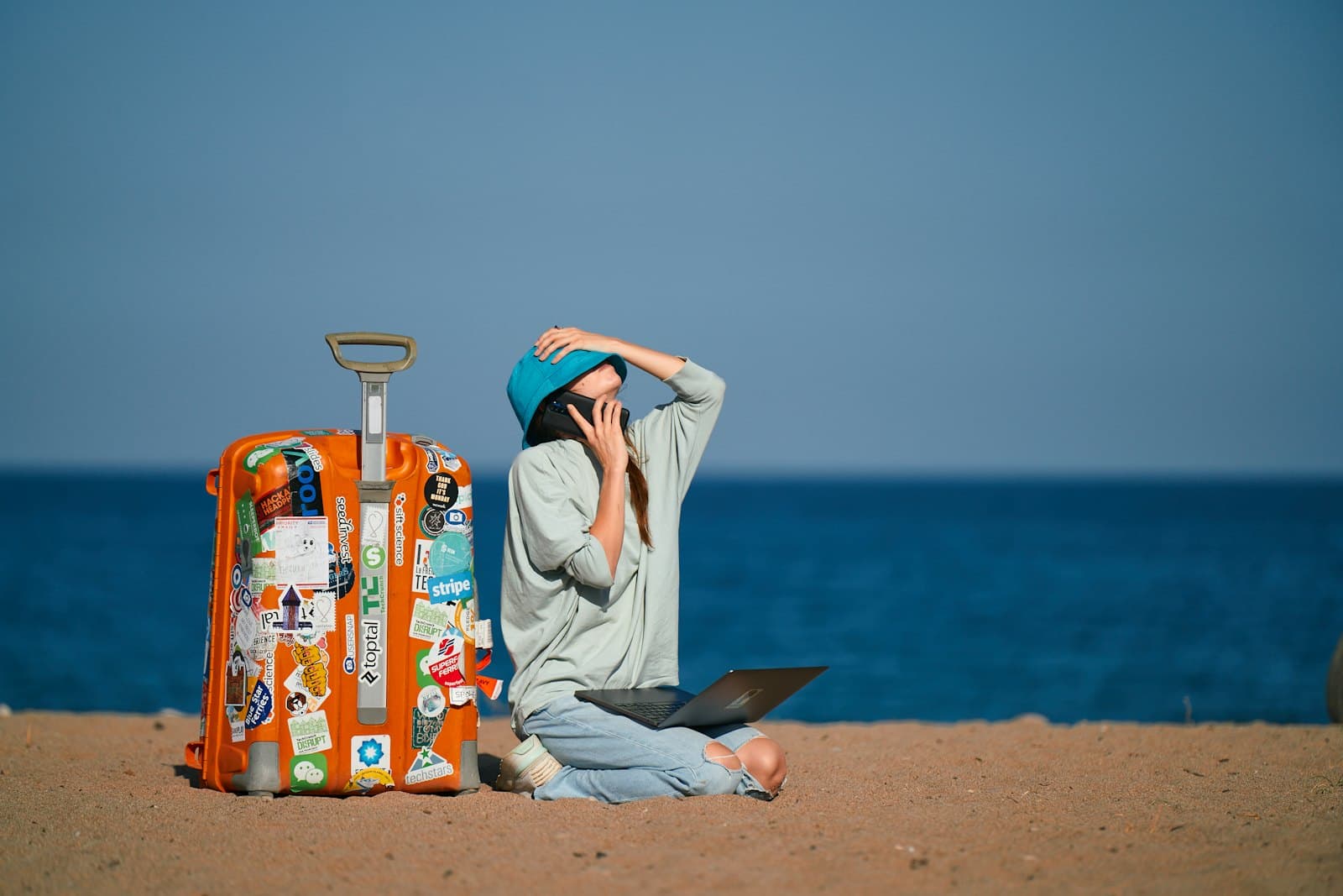 Une voyageuse assise sur sa valise face à la mer