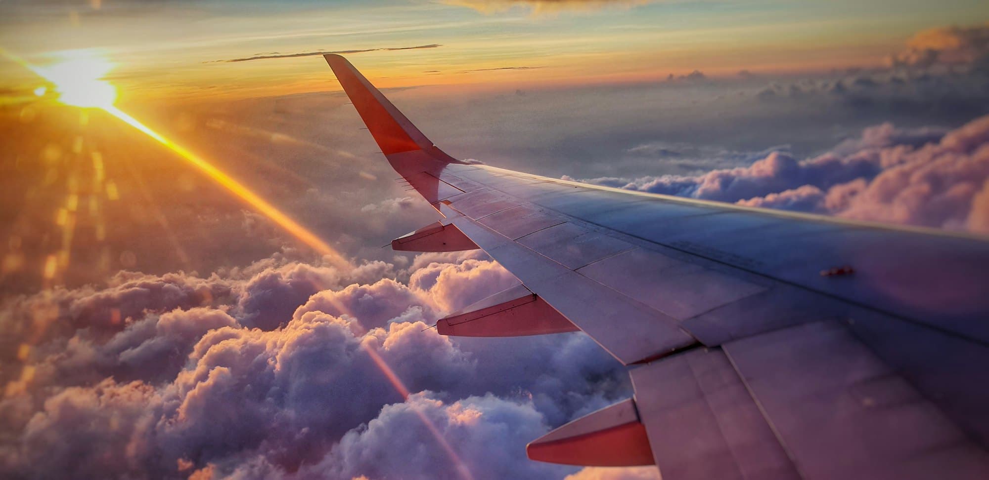 Aile d'avion au-dessus des nuages au coucher du soleil